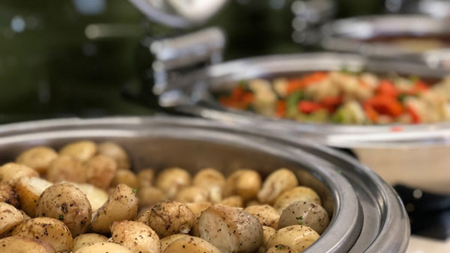 Hot roasted potatoes sprinkled with herbs and pepper sitting in dish