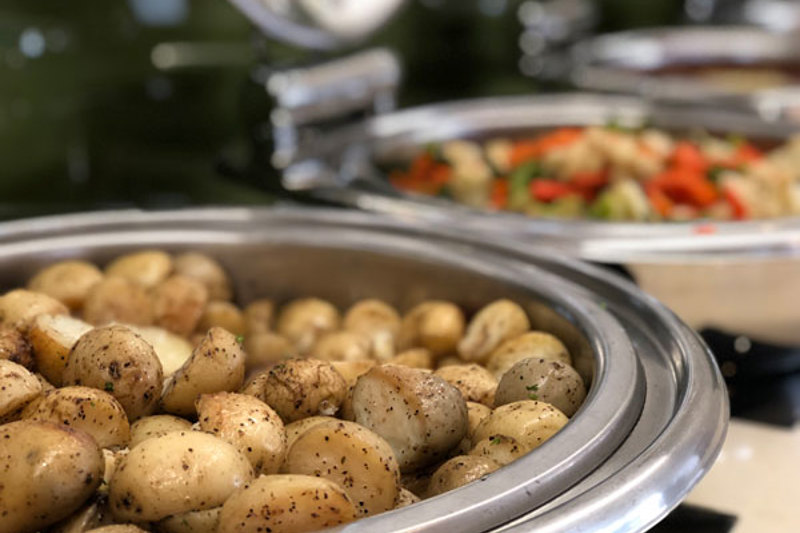 Hot roasted potatoes sprinkled with herbs and pepper sitting in dish