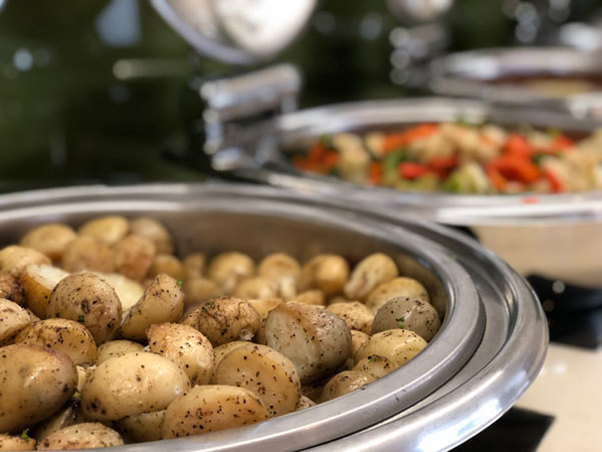 Hot roasted potatoes sprinkled with herbs and pepper sitting in dish