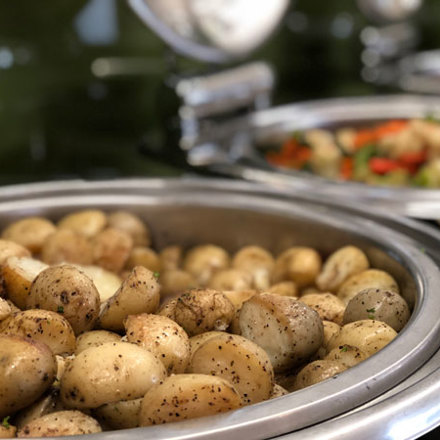 Hot roasted potatoes sprinkled with herbs and pepper sitting in dish