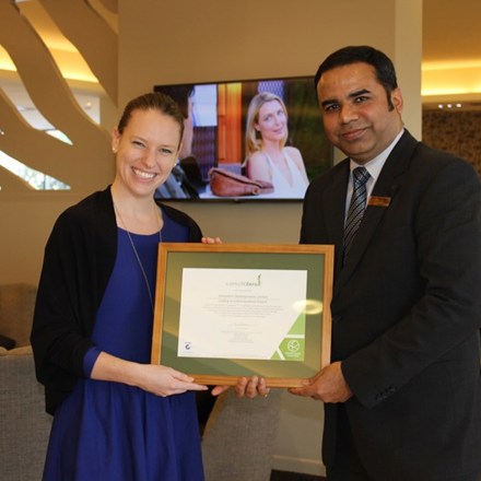 Two people smiling and holding a framed certificate.