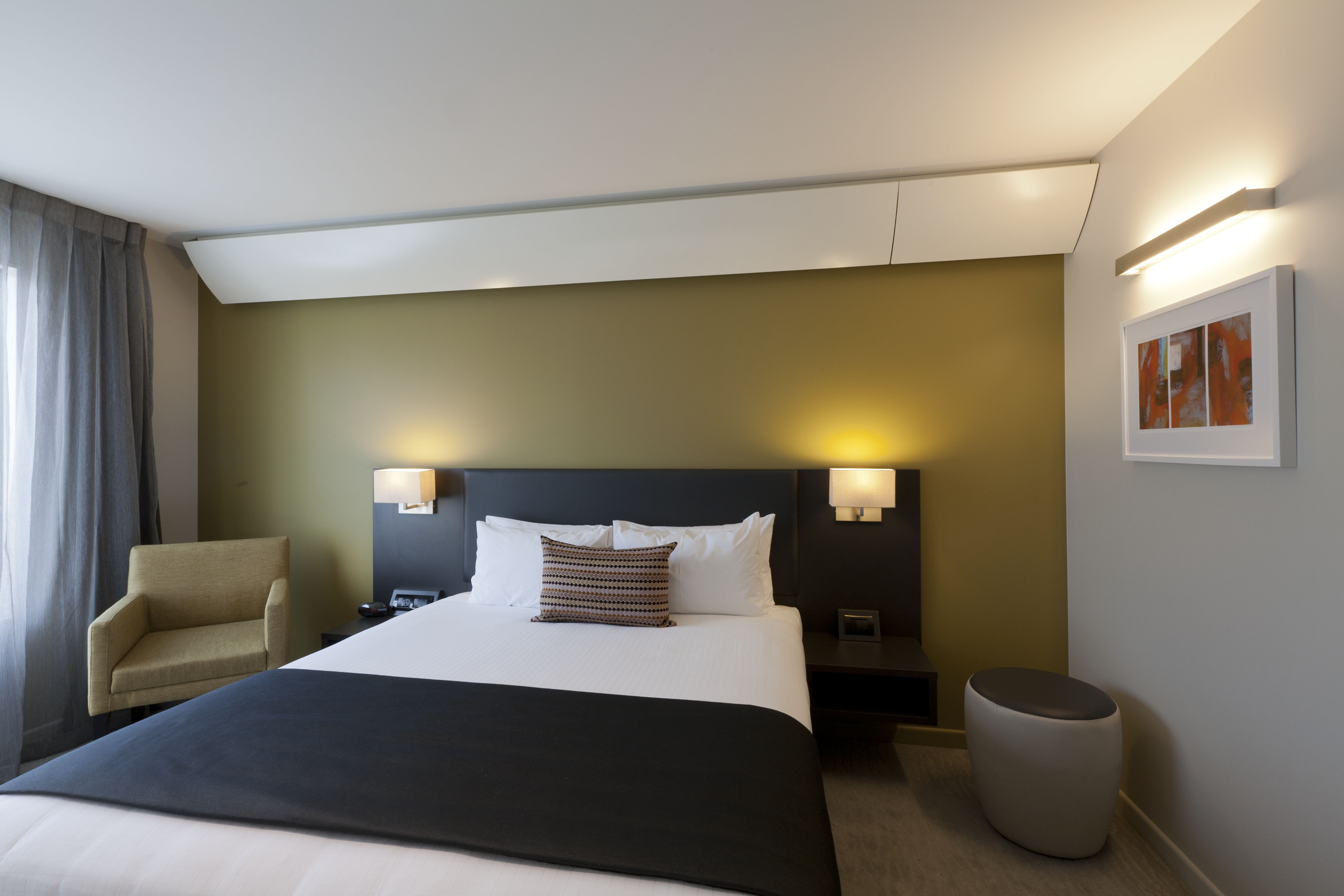 Executive king room with lounge seat and ottoman painting on right wall