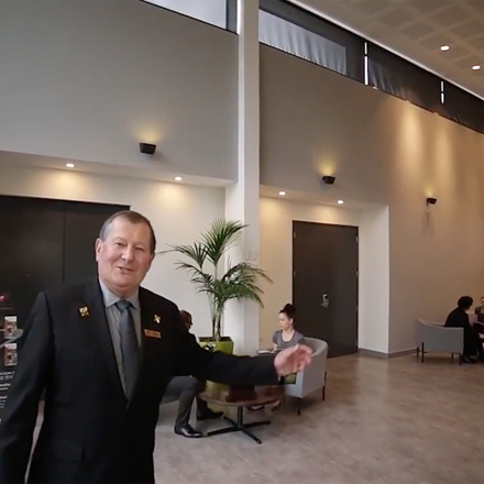 Older customer service man greeting hello and extending arm in welcoming gesture.