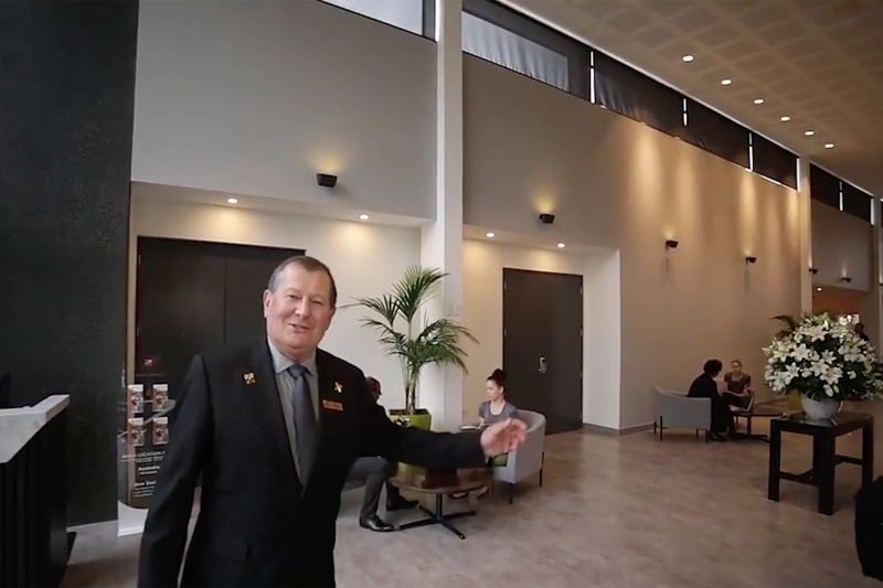 Older customer service man greeting hello and extending arm in welcoming gesture.