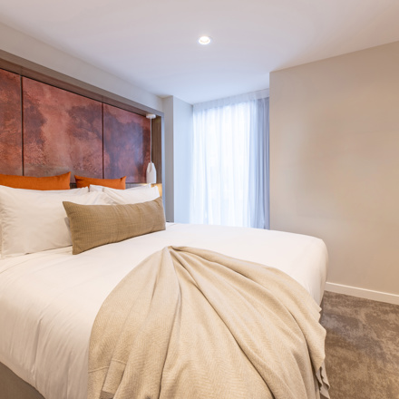 Luxury king bed with luxury linen and furnishings including flatscreen on wall and art on headboard. 