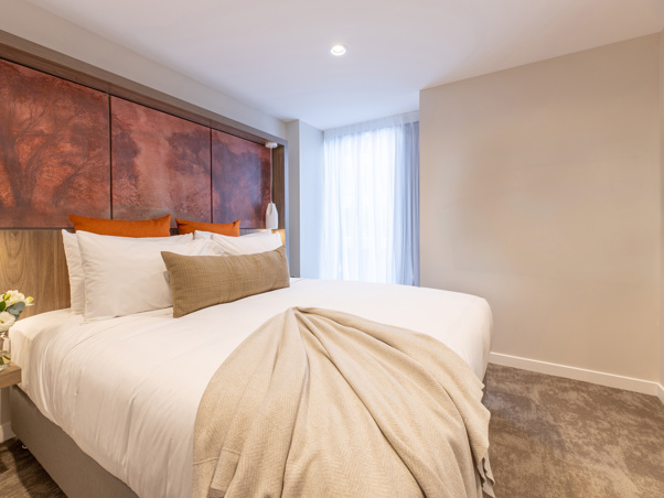 Luxury king bed with luxury linen and furnishings including flatscreen on wall and art on headboard. 