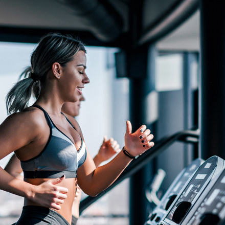 Two girls running on treadmill be a window.