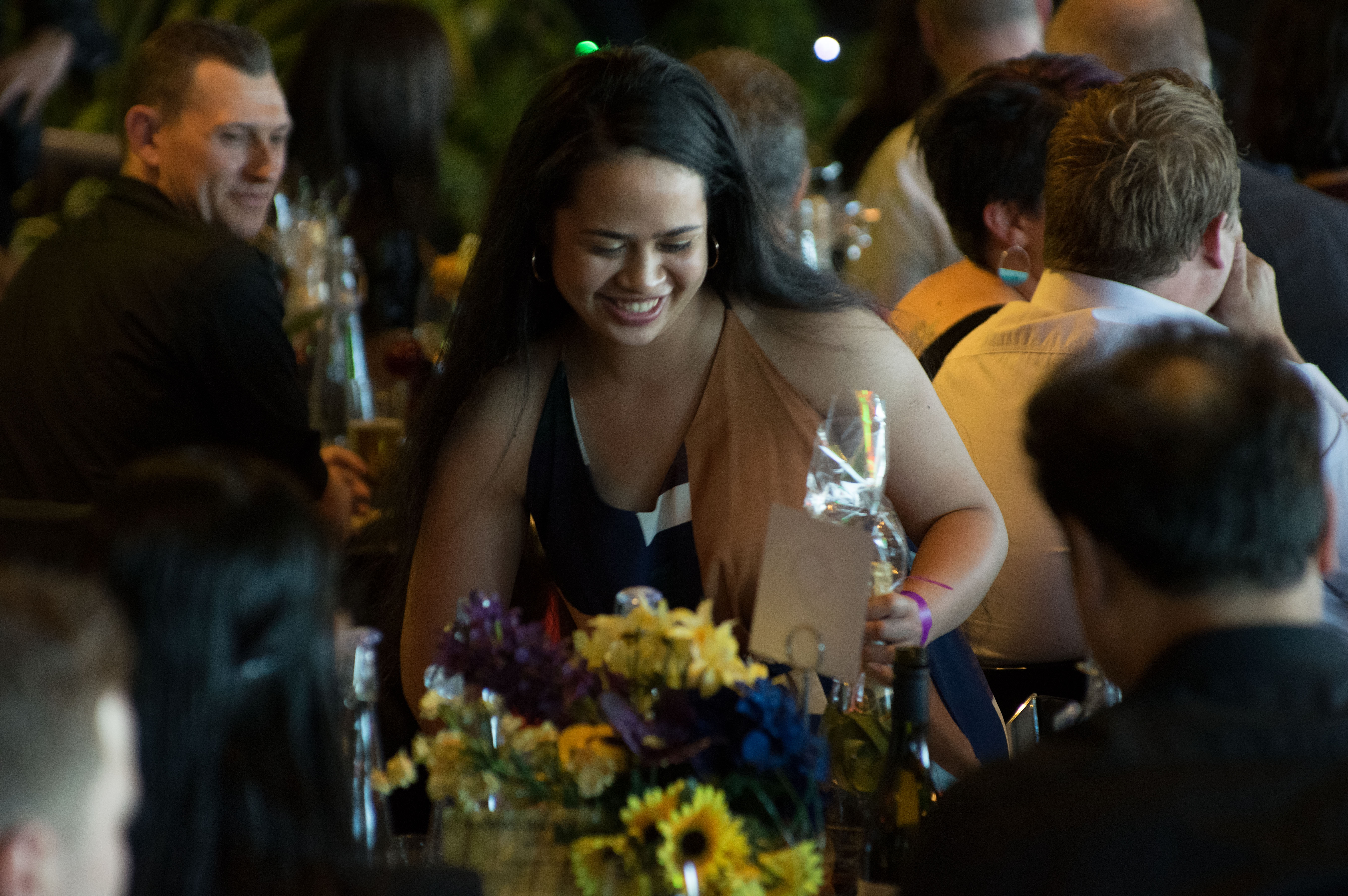 Girl sitting back at table after collecting prize at awards event