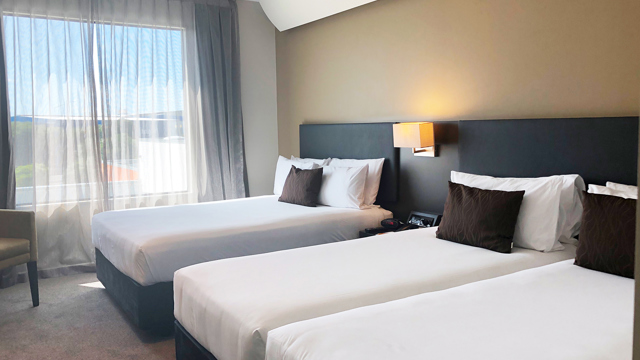 Superior triple room with three beds. Large windows letting in lots of natural light. Has flatscreen TV, lamps and lounge chair.