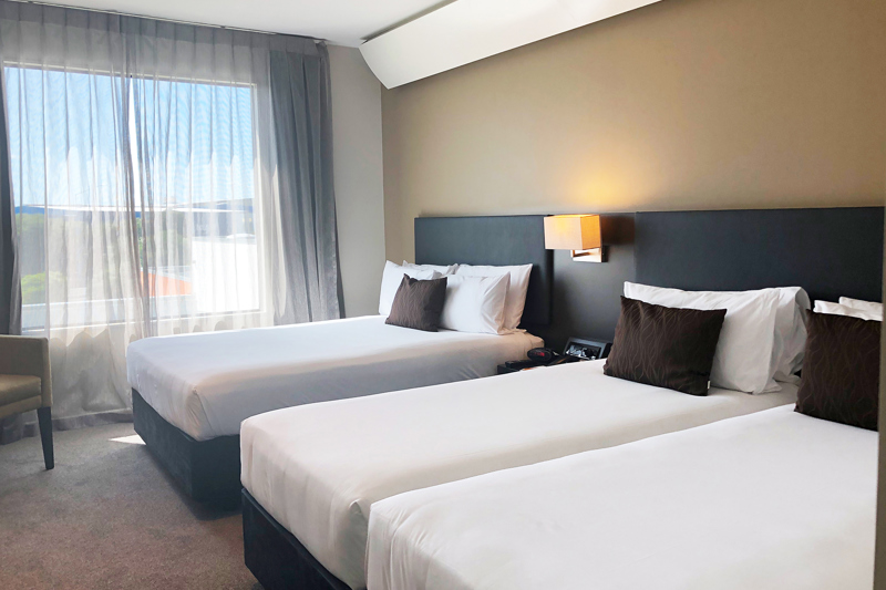 Superior triple room with three beds. Large windows letting in lots of natural light. Has flatscreen TV, lamps and lounge chair.