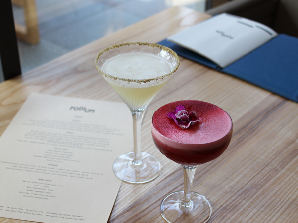 One pink and one lemon cocktail in martini style glasses on table