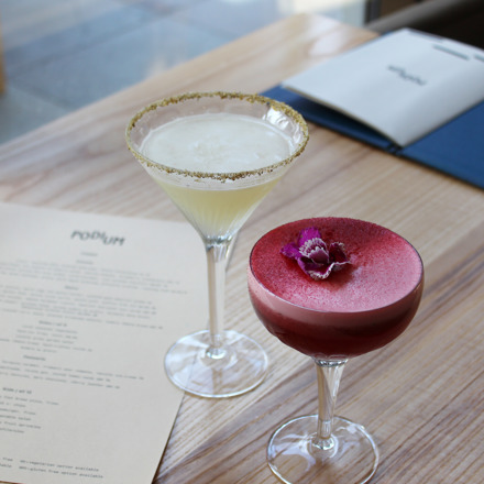 One pink and one lemon cocktail in martini style glasses on table