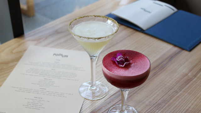 One pink and one lemon cocktail in martini style glasses on table