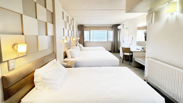 Classic Triple room with 1 double bed and 2 single beds and desk and chair.
