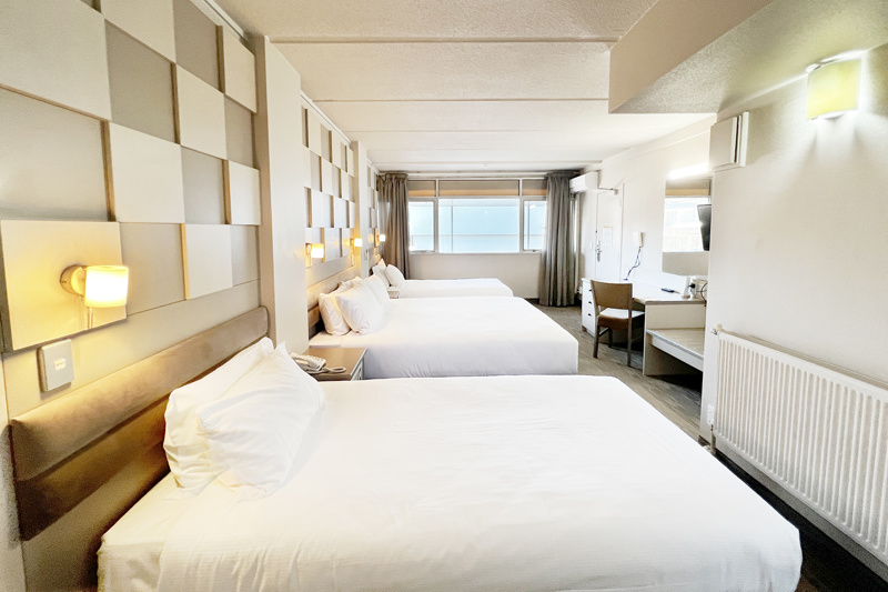 Classic Triple room with 1 double bed and 2 single beds and desk and chair.